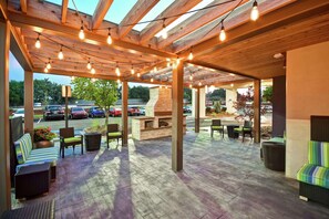 An outdoor patio area with wooden beams, string lights, and seating arrangements. - Home2 Suites by Hilton Atlanta Norcross (Norcross)