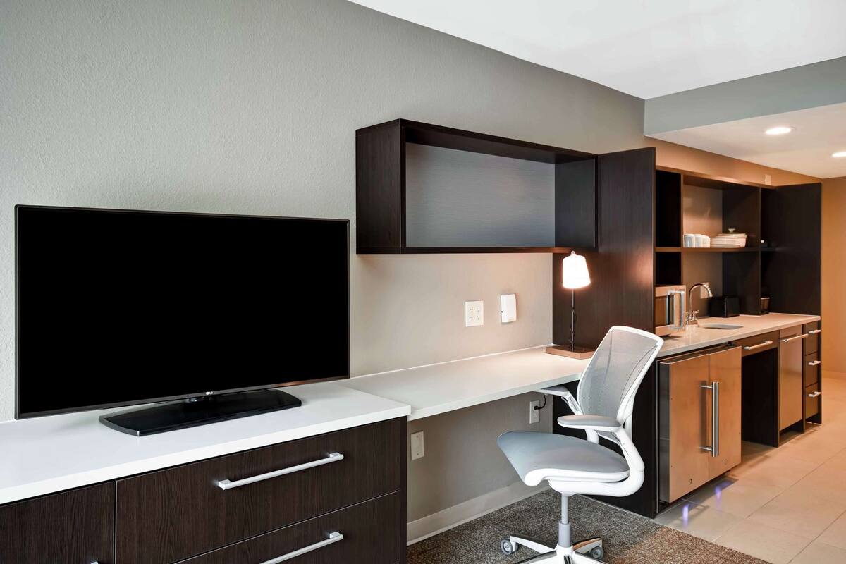 A modern kitchen with a flat-screen TV, a built-in oven, and a sink.