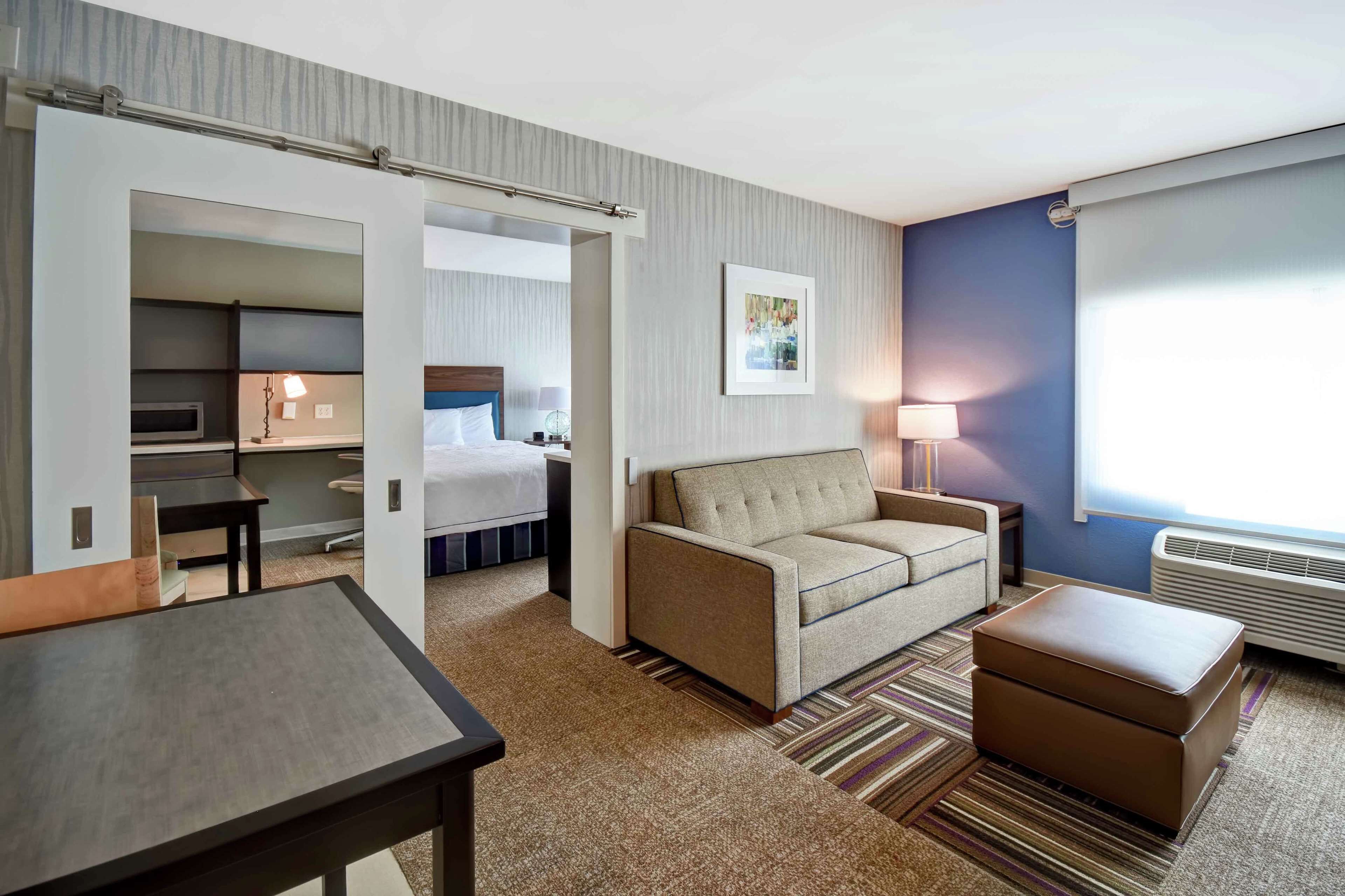 Una habitación de hotel con cama, sofá, mesa y kitchenette.