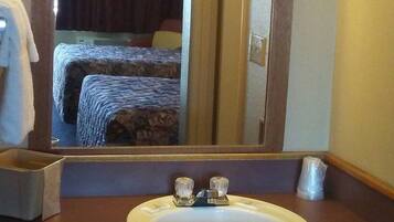 Un baño de hotel con un espejo grande, un lavamanos y un perchero para toallas.