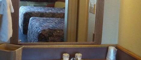Une salle de bain d’hôtel avec un grand miroir, un lavabo et un porte-serviettes.