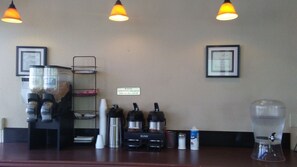 A coffee station with a sign indicating continental breakfast hours, coffee makers, cups, and a water dispenser. - Cedars Inn Lewiston (Lewiston)