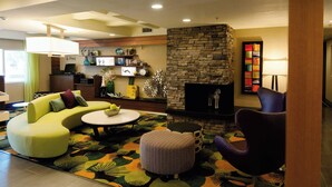 A modern living room with a stone fireplace, a green sofa, a round coffee table, and a purple armchair. - Fairfield Inn by Marriott St. George (St. George)