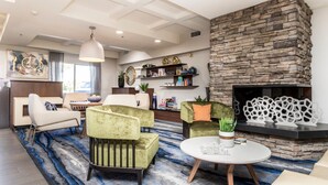 A modern living room with a stone fireplace, plush seating, and a decorative ceiling. - Fairfield Inn by Marriott St. George (St. George)