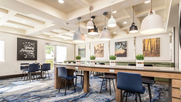 A modern conference room with a long table, multiple chairs, pendant lighting, and artwork on the walls. - Fairfield Inn by Marriott St. George (St. George)