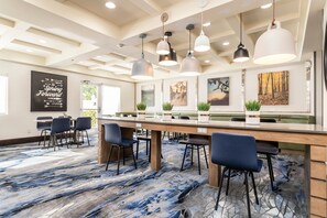 A modern conference room with a long table, multiple chairs, pendant lighting, and artwork on the walls. - Fairfield Inn by Marriott St. George (St. George)