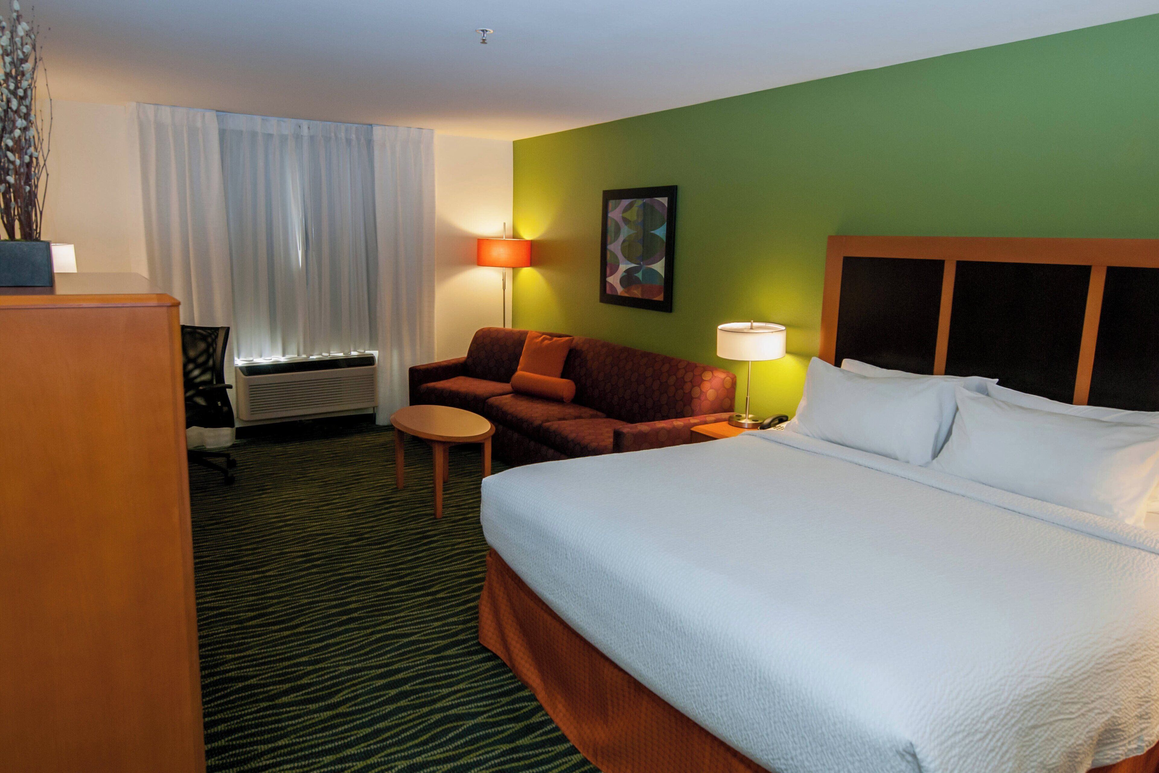 Une chambre d’hôtel avec un grand lit, un canapé, une petite table et un bureau.