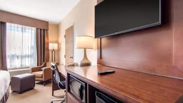 Hotelkamer met een bed, een bureau met lamp, een televisie, een stoel en een magnetron.