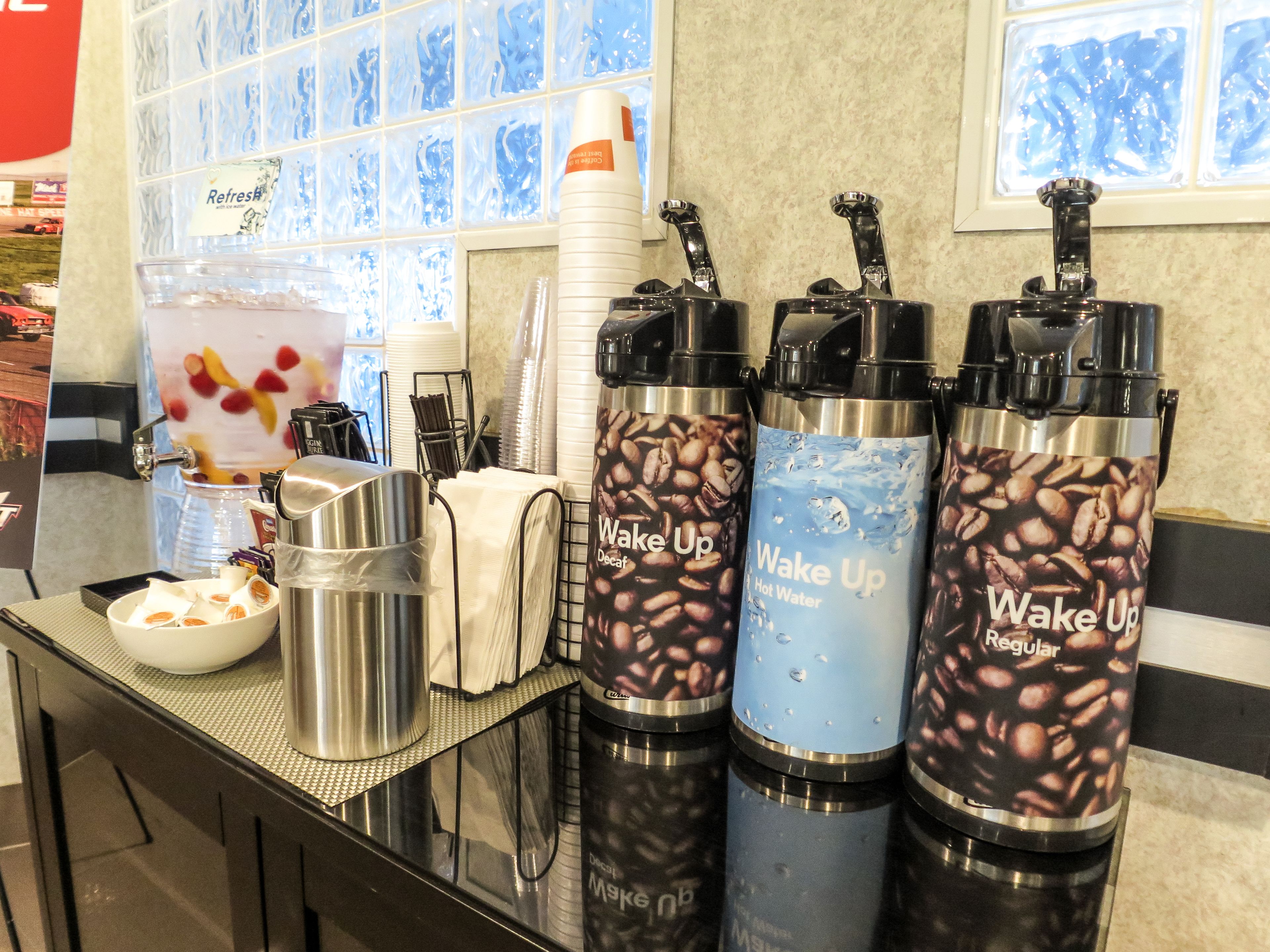 A coffee station with three coffee dispensers labeled "Wake Up" and a water dispenser.