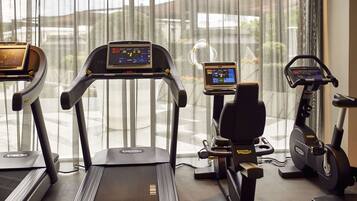 A gym with treadmills, an elliptical, and a stationary bike, all equipped with digital displays.