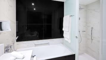 Une salle de bain moderne avec un grand miroir, une baignoire, un espace douche et des murs en marbre.