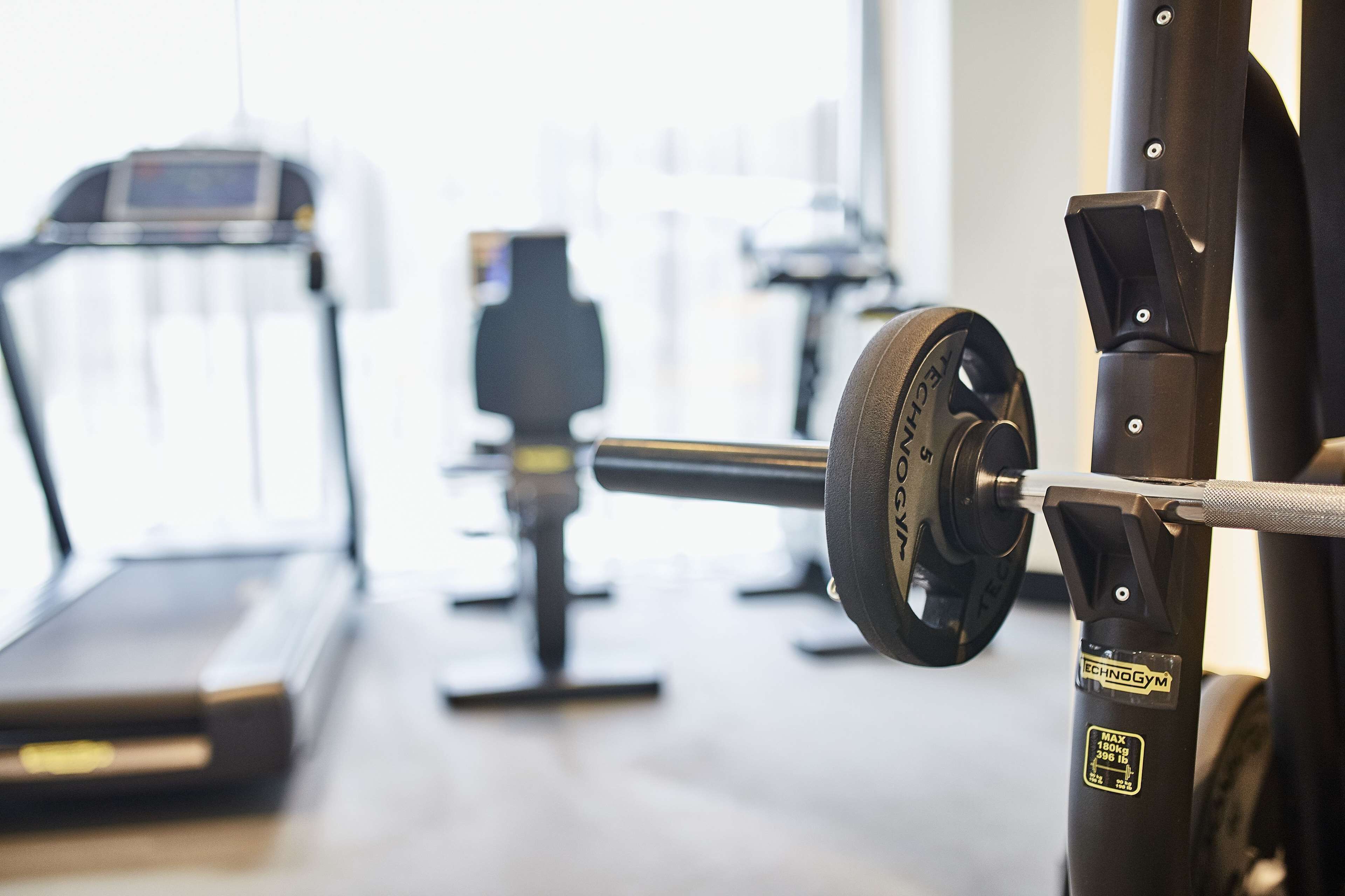 Un gimnasio con cinta de correr, prensa de banca y una torre de pesas.