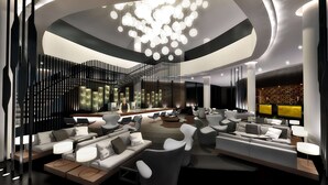 A modern lobby with a central staircase, seating areas, and a large chandelier. - Hilton Tallinn Park (Tallinn)