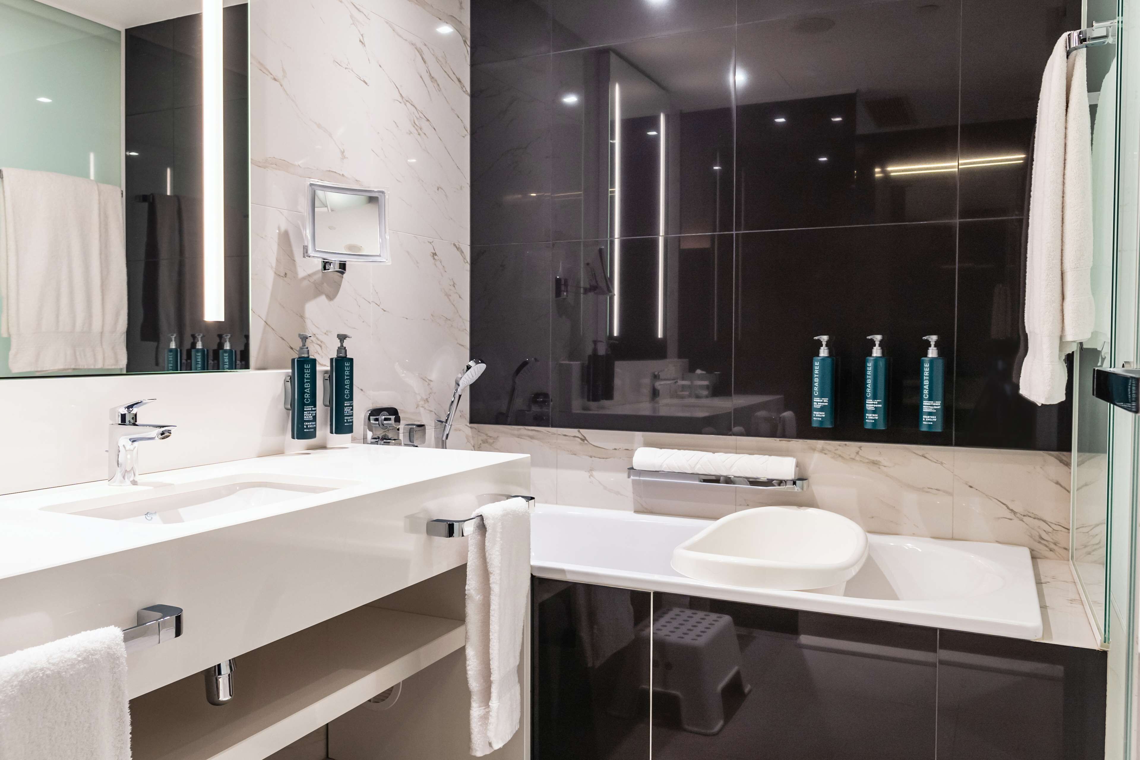 A modern bathroom with two sinks, a large mirror, and a glass-enclosed shower area.