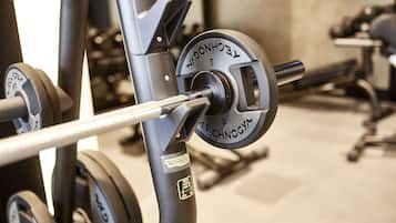 Een detailopname van een krachttrainingapparaat met een stang, gewichtsschijven en een label met de tekst 'TECHNOGYM'.