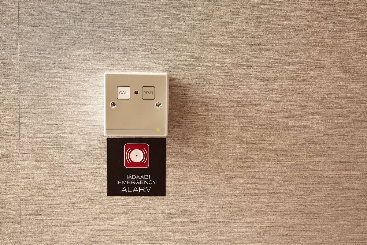 Un pulsante di allarme di emergenza fissato a parete, con un’etichetta.
