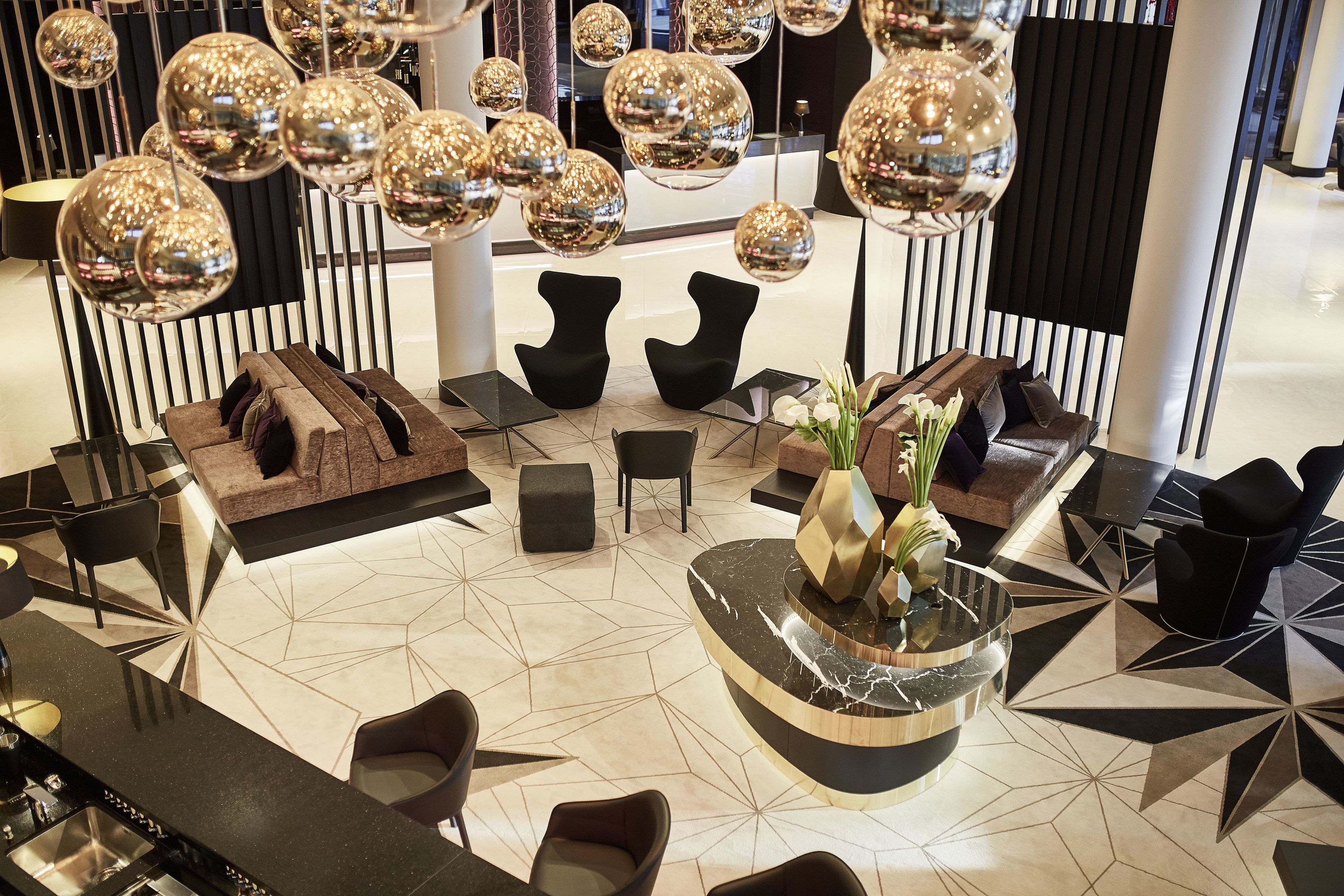 A modern lobby with a central seating area, a reception desk, and decorative spherical mirrors.