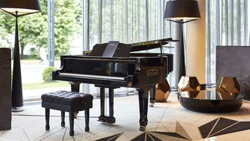 A grand piano in a well-lit room with a modern design, including a geometric patterned rug and contemporary furniture.