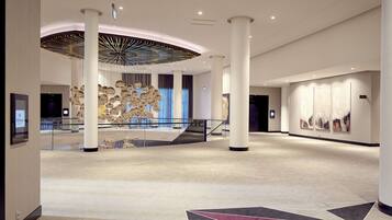 A spacious lobby with high ceilings, a central staircase, and a modern chandelier.
