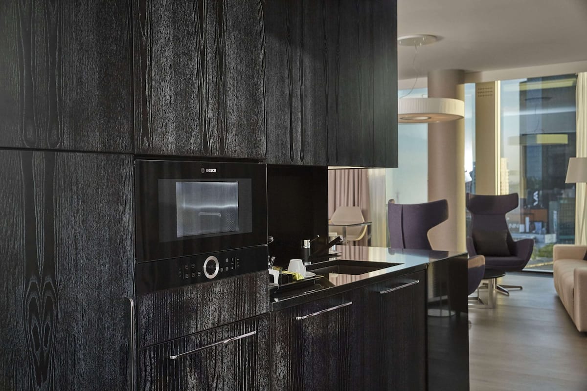 Una cucina moderna con un forno a microonde Bosch, mobili in legno scuro e un'elegante isola con lavello.