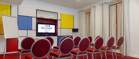 Ein Konferenzraum mit rotem Teppich, weißen Wänden und einer Projektionsleinwand, die "Hôtel La Résidence du Vieux Pont" zeigt.