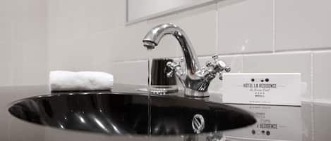 A black sink with a chrome faucet and a white towel. A sign with hotel information is visible.