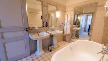 Une salle de bain avec deux lavabos, une grande baignoire et une porte.