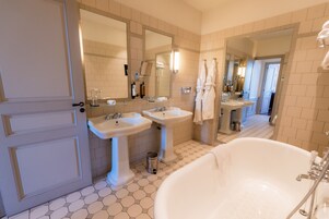 Une salle de bain avec deux lavabos, une grande baignoire et une porte.