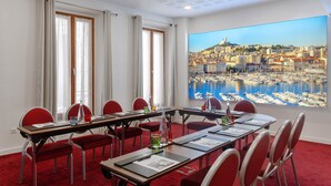 A conference room with a cityscape view, red chairs, a long table, and a red carpet.