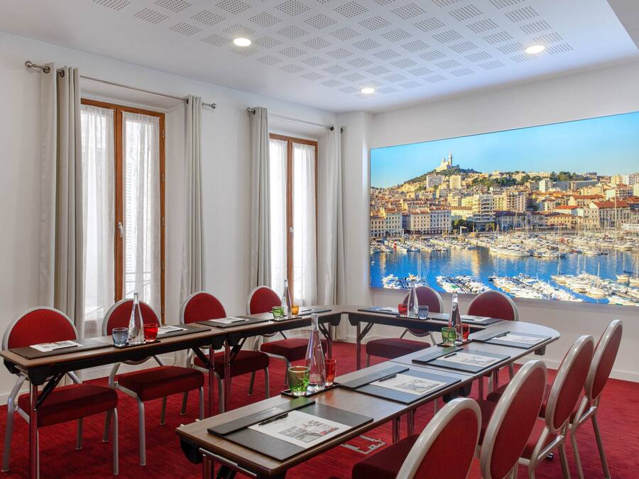A conference room with a cityscape view, red chairs, a long table, and a red carpet.