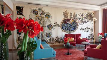 Un salon moderne avec un canapé bleu, des fauteuils rouges et un tapis rouge.