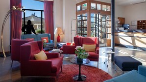A modern living room with red sofas, a coffee table, and a large window with curtains.
