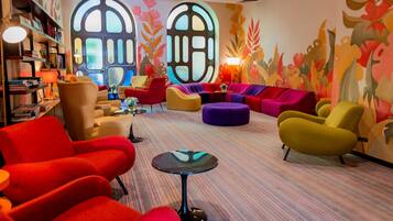 Un salón vibrante con asientos coloridos, una mesita y una estantería.