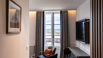 A hotel room with a large window, a television, a table, and two chairs.