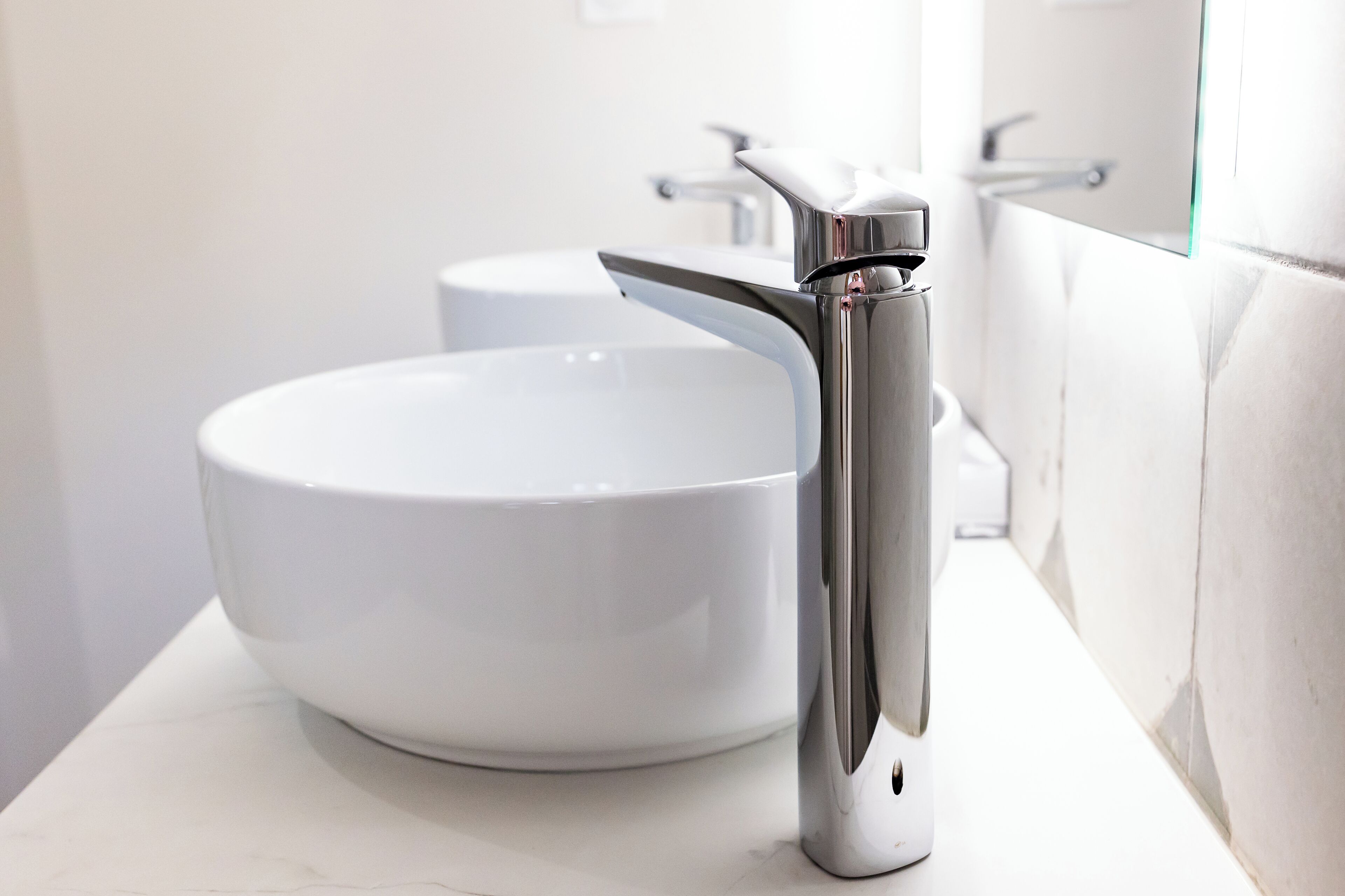 Un baño moderno con un lavamanos blanco y grifo cromado.