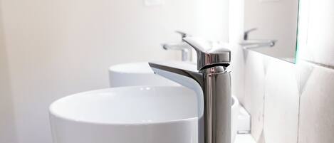 Un baño moderno con un lavamanos blanco y grifo cromado.
