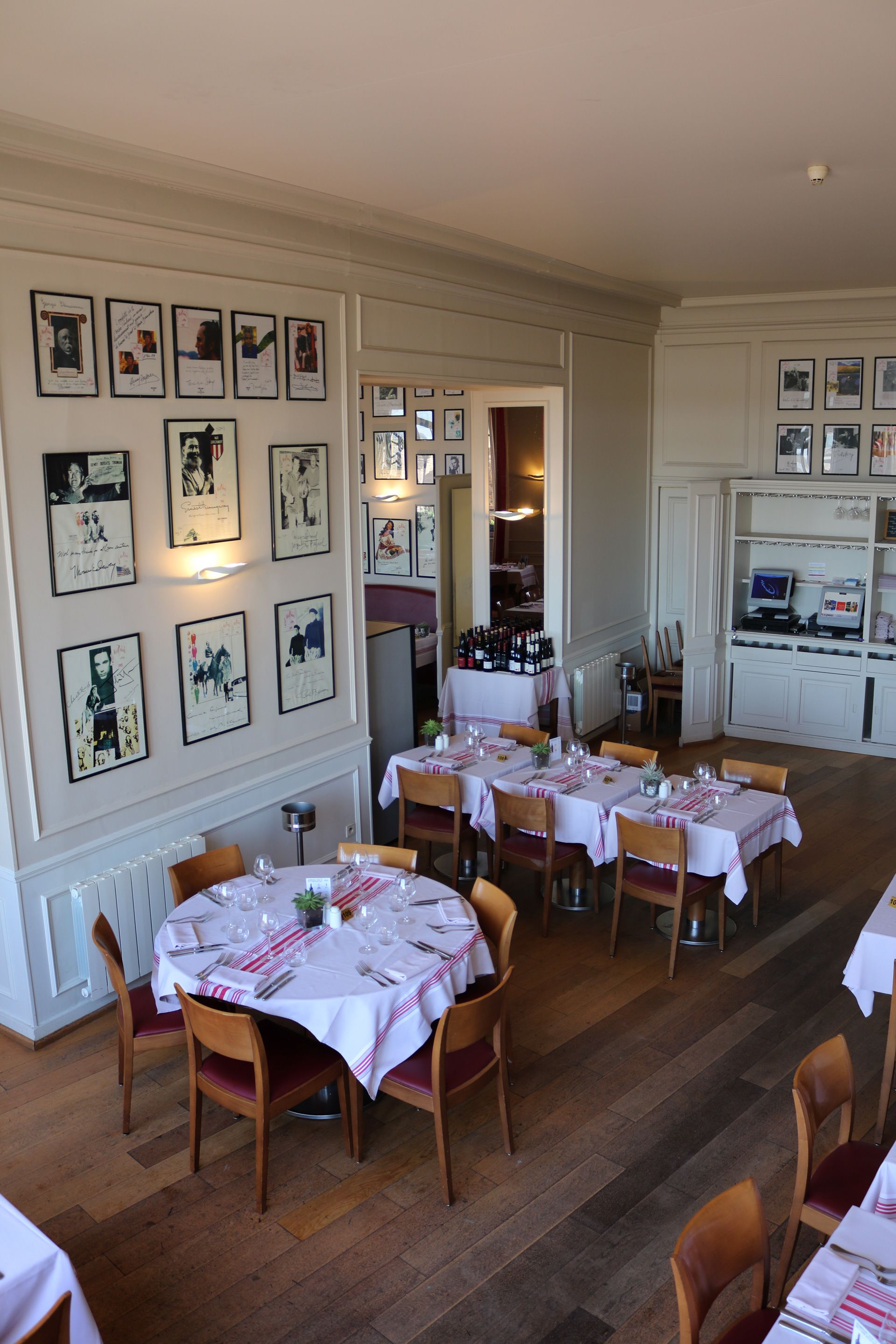 Un comedor con varias mesas dispuestas para recibir a los huéspedes, con una variedad de cuadros enmarcados en las paredes.