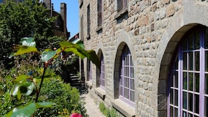 A stone building with arched windows and a pathway leading to the entrance.