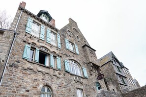 Un edificio storico in pietra con numerose finestre e persiane, con un cartello ben visibile dell'Hotel Ermitage.