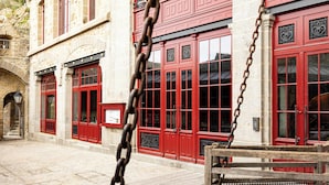 A stone building with red doors and windows, a cobblestone street, and a wooden bench.