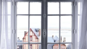 A view through a window with a white frame, revealing buildings with red and white facades and a snowy landscape.