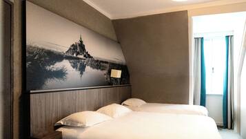 A hotel room with a large bed, a nightstand, and a wall-mounted painting of a castle.