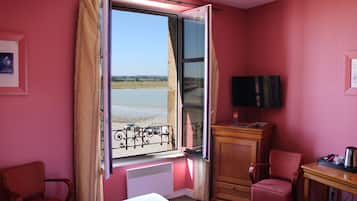 Enjoy a beachside view from the comfort of this room, featuring a bed, TV, and seating area.