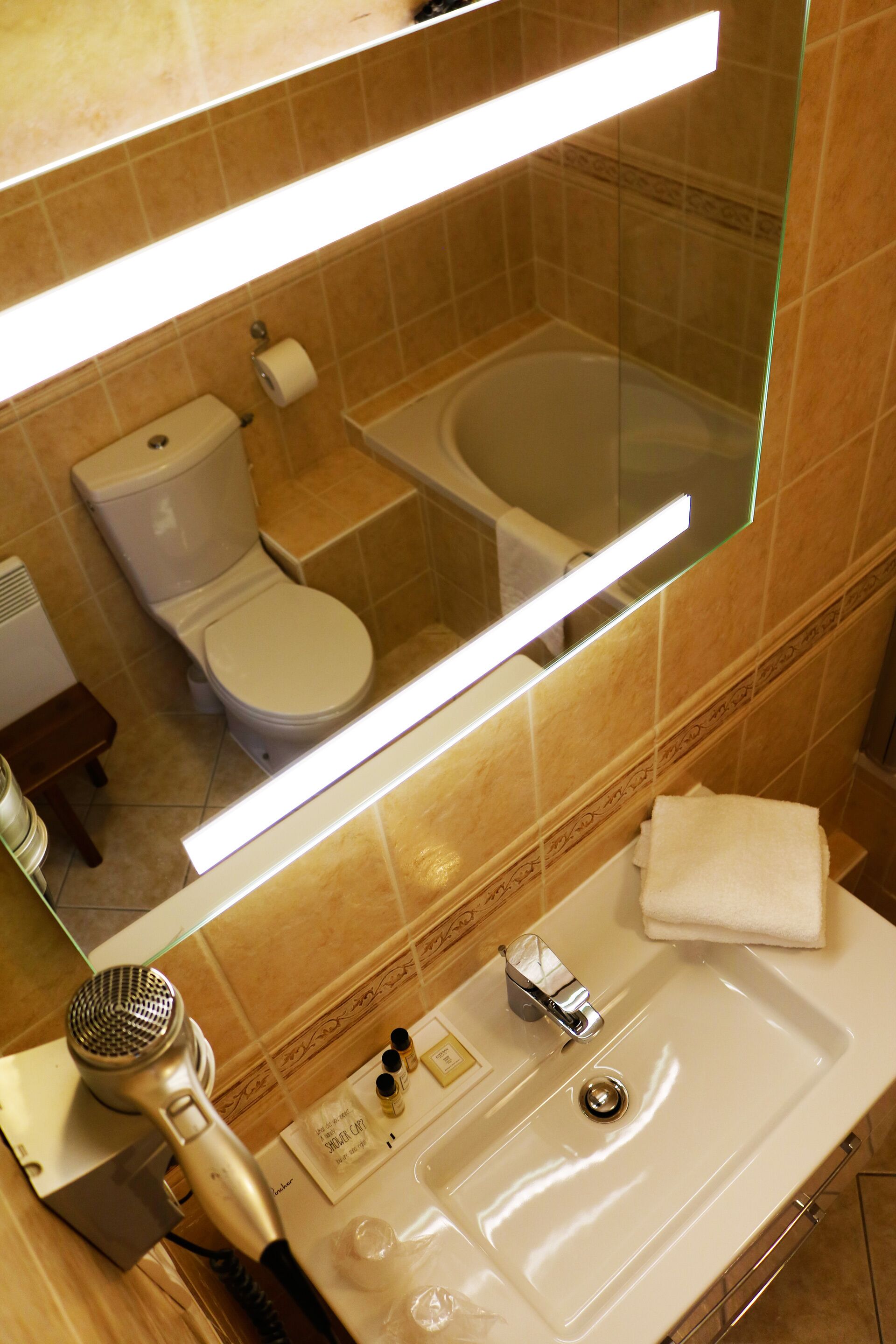 Un baño con inodoro, lavamanos y secador de pelo.