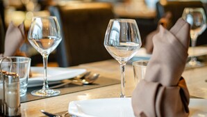 A dining table set with wine glasses, plates, and cutlery, with a napkin folded on the plate. - Logis Hotel Restaurant des Acacias Lille Tourcoing (Neuville-en-Ferrain)