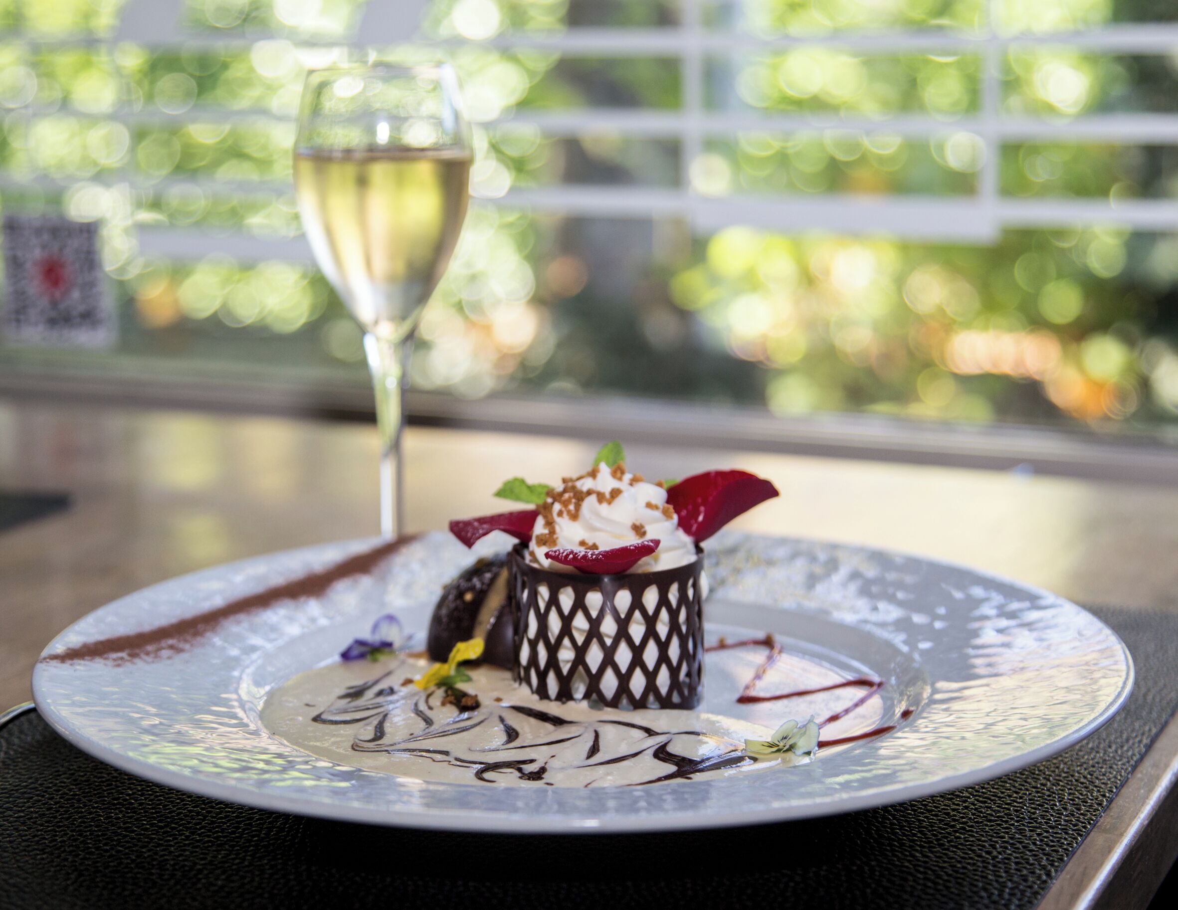 A dessert on a plate with a glass of white wine in the background.