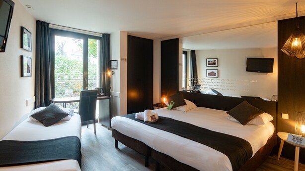 A hotel room with two beds, a TV, a desk, and a balcony with curtains. - Logis Hotel Restaurant des Acacias Lille Tourcoing (Neuville-en-Ferrain)