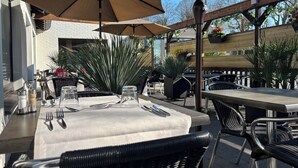 An outdoor dining area with tables and chairs, umbrellas, and potted plants. - Logis Hotel Restaurant des Acacias Lille Tourcoing (Neuville-en-Ferrain)