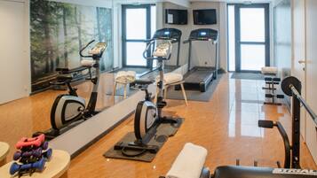 A gym with exercise equipment, a treadmill, and a mirror.