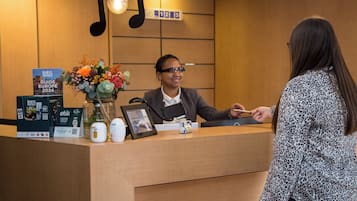 Una recepción de hotel con una foto enmarcada, arreglos florales y material promocional.